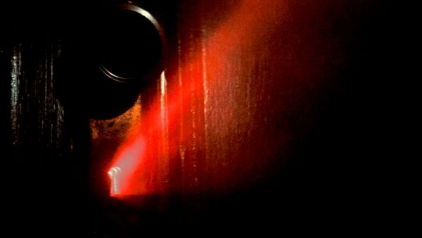 Image from Close Encounters of the Third Kind in which an eerie red light glows from within a keyhole in a door.