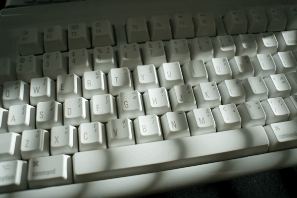 Close up view of sunlight falling across the keys on a white, Mac-style mechanical keyboard